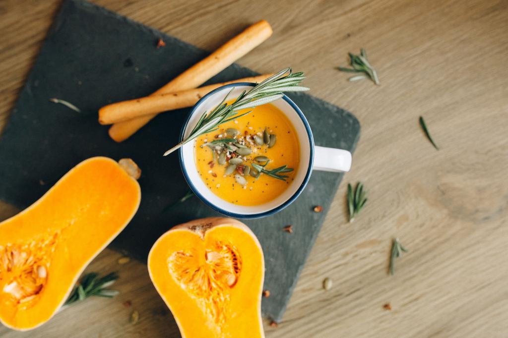Eine herzhafte Kürbissuppe, serviert mit frischem Rosmarin und Samen, perfekt für Herbstgerichte.